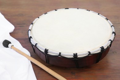 Photo of Modern drum with drumstick on wooden table