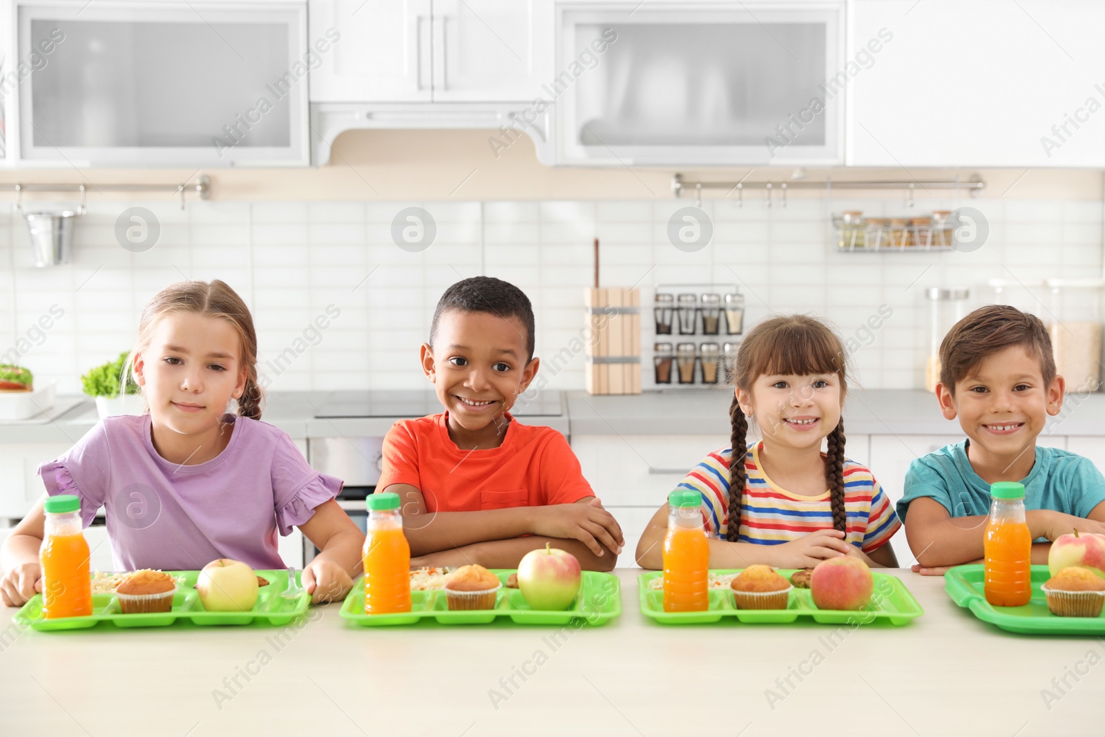 Photo of Children sitting at table and eating healthy food during break at school