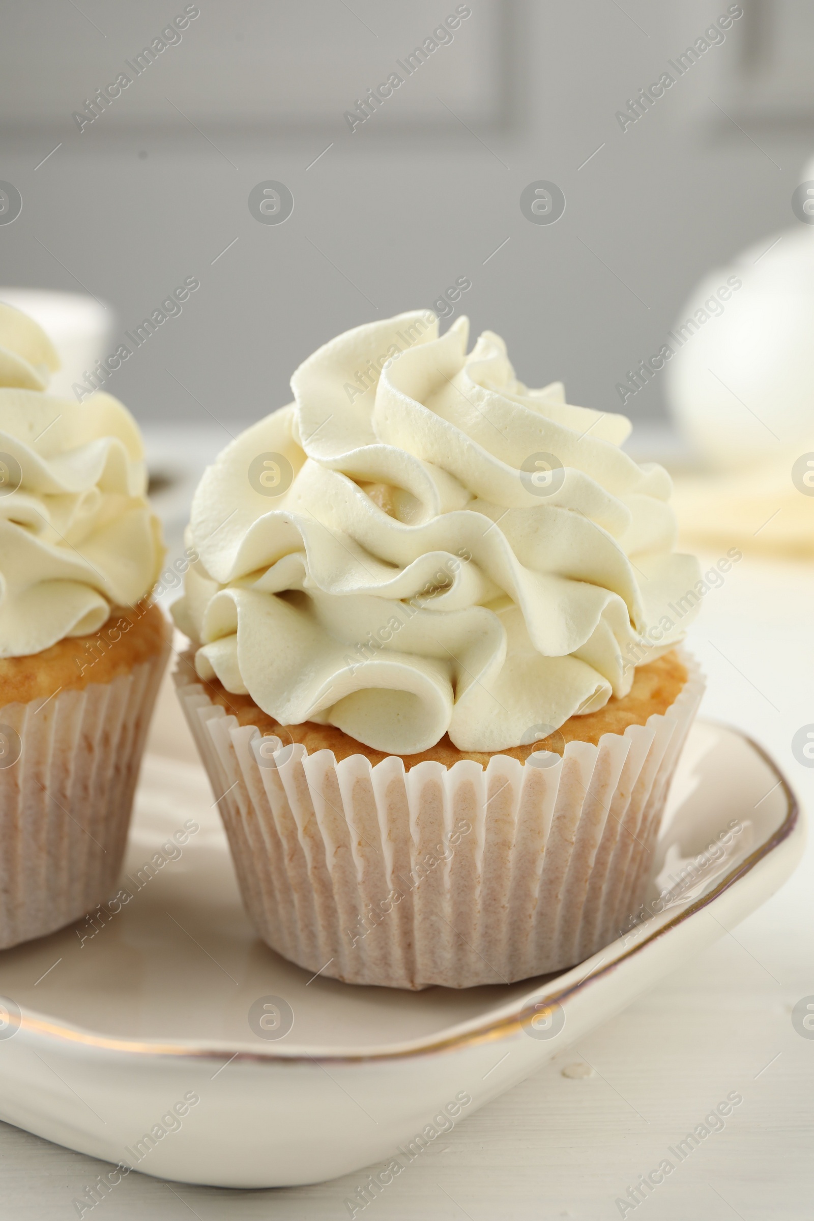 Photo of Tasty cupcakes with vanilla cream on white wooden table, closeup