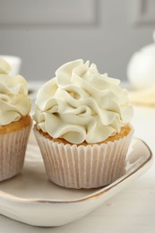 Photo of Tasty cupcakes with vanilla cream on white wooden table, closeup