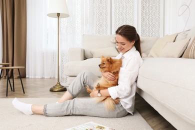 Happy young woman with cute dog in living room