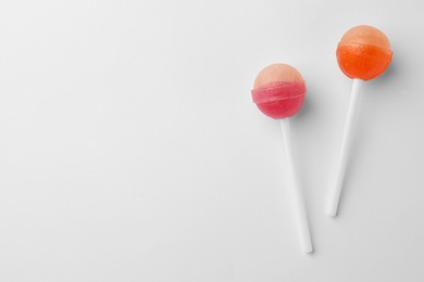 Photo of Tasty lollipops on white background, flat lay. Space for text