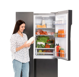 Photo of Young woman with bottle of milk near open refrigerator on white background