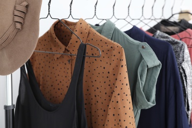 Different stylish clothes on rack indoors, closeup