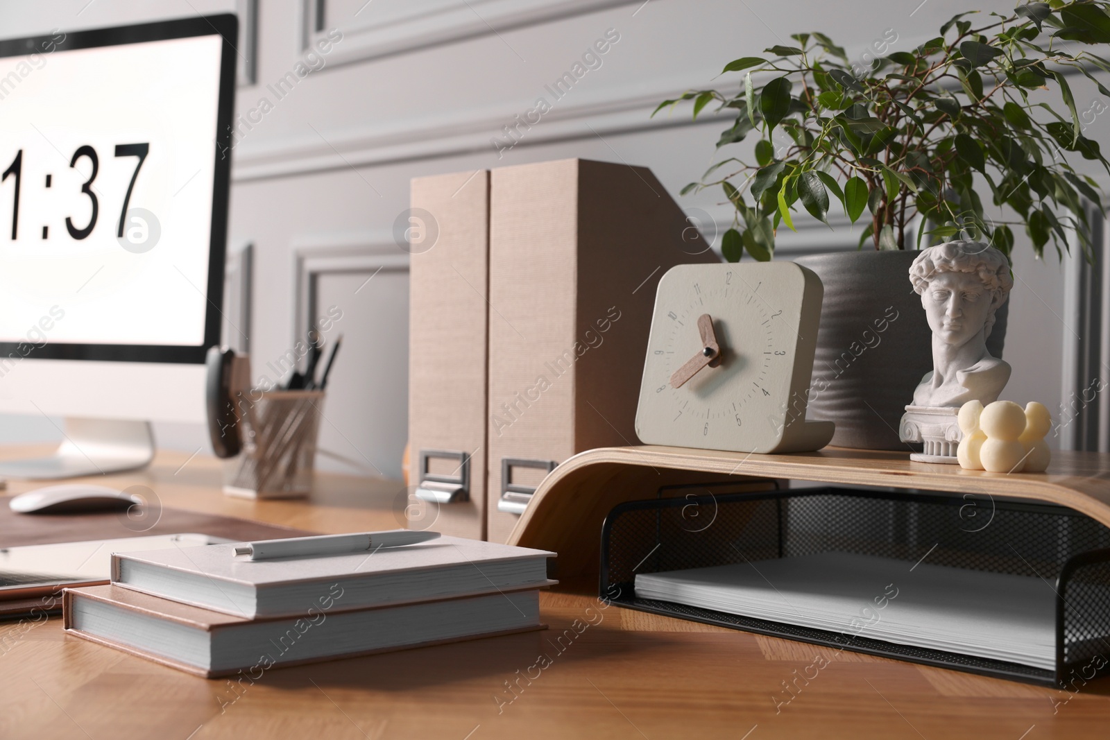 Photo of Stylish workplace with computer, houseplant and stationery on wooden desk near grey wall at home