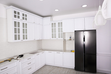 Photo of Renovated kitchen interior with stylish furniture, refrigerator and maintenance equipment