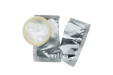 Torn package with condom isolated on white, top view. Safe sex