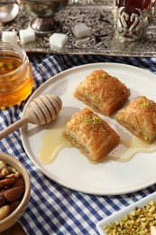 Photo of Delicious sweet baklava with pistachios and honey on table, closeup