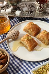 Delicious sweet baklava with pistachios and honey on table, closeup