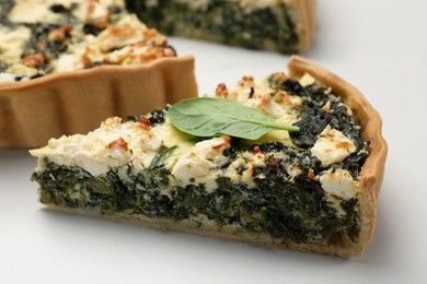 Delicious homemade spinach quiche on white table, closeup