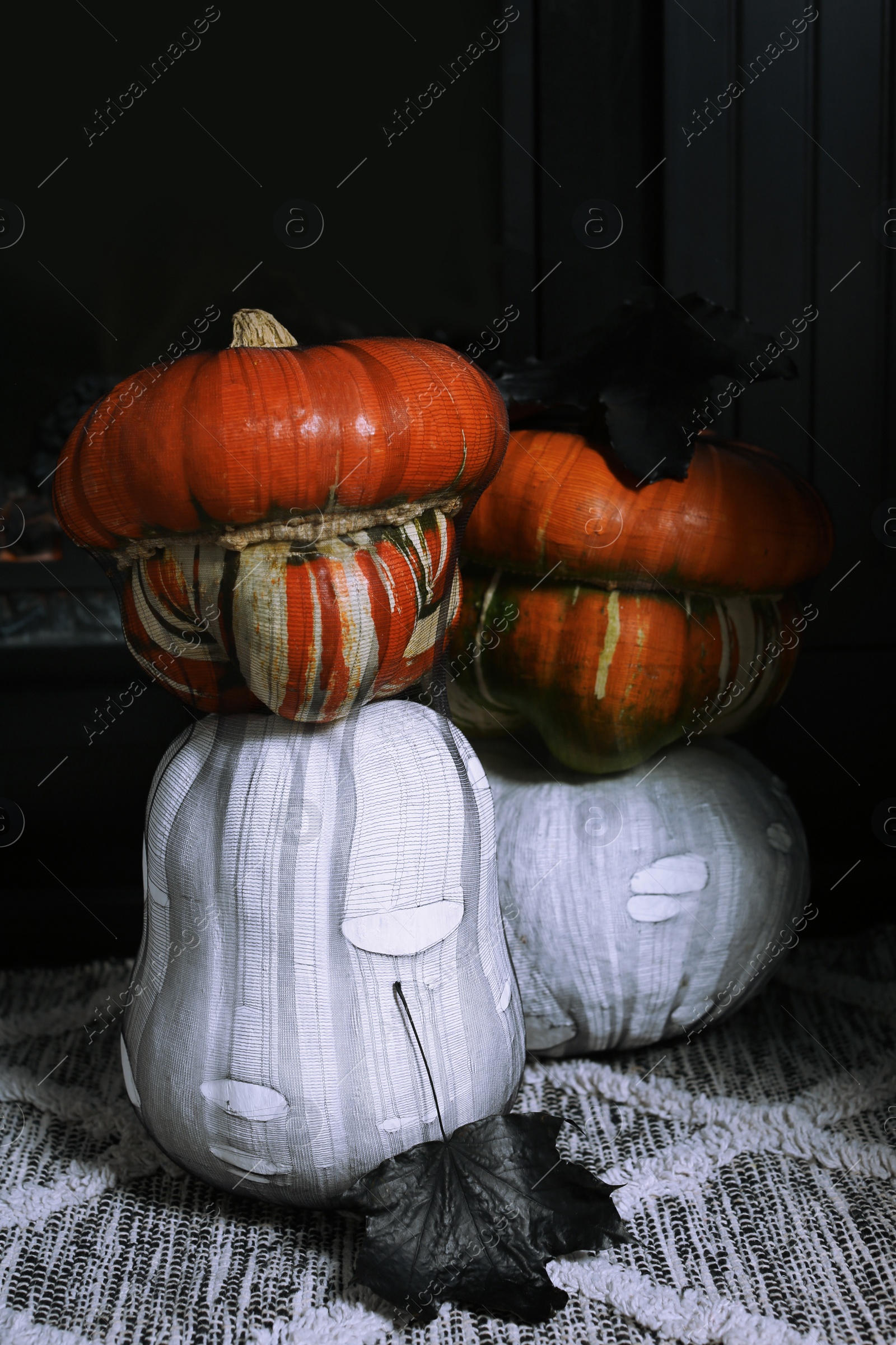 Photo of Colorful pumpkins on rug near fireplace. Halloween decorations