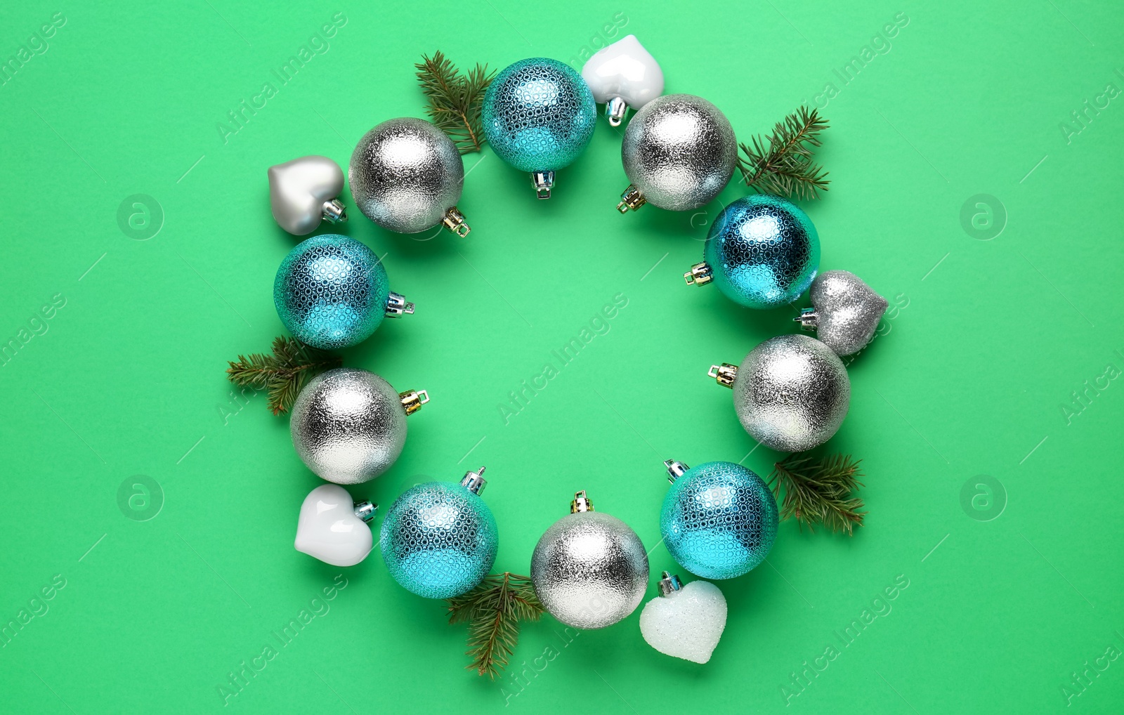 Photo of Beautiful festive wreath made of color Christmas balls and fir tree branches on green background, top view