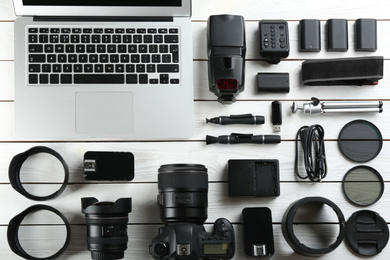 Flat lay composition with equipment for professional photographer on white wooden table