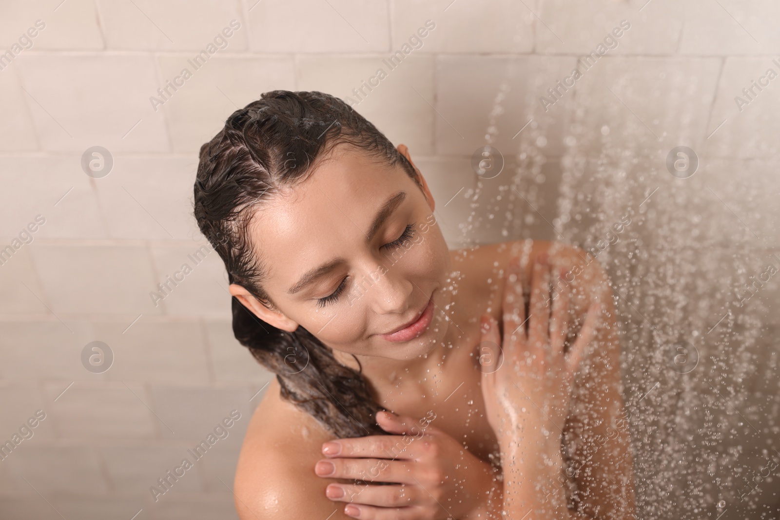 Photo of Young woman washing hair while taking shower at home, above view