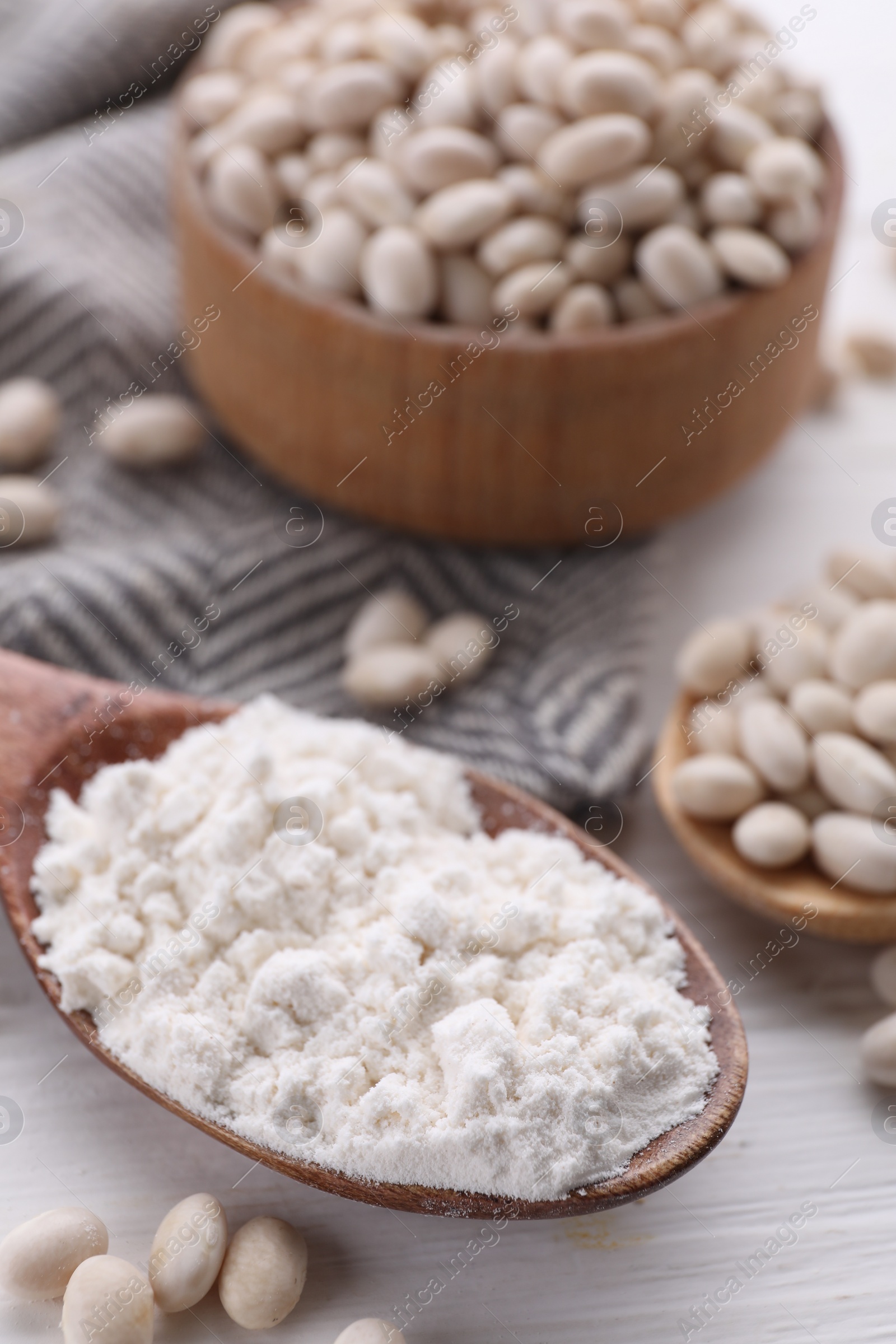 Photo of Kidney bean flour and seeds on white wooden table, closeup