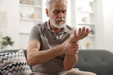 Arthritis symptoms. Man suffering from pain in wrist at home