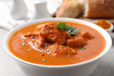 Photo of Bowl of delicious chicken curry on light grey table, closeup