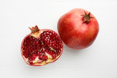 Fresh pomegranates on white wooden table, top view