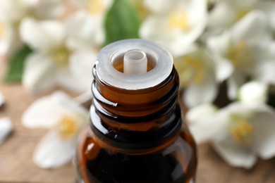 Photo of Bottle of natural jasmine essential oil on table, closeup