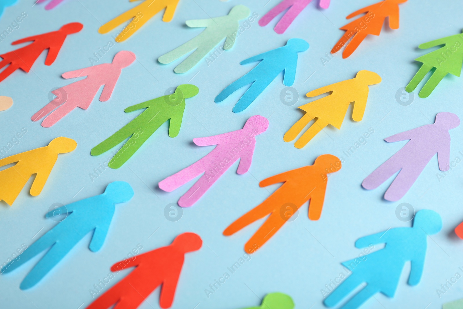 Photo of Many different paper human figures on light blue background. Diversity and inclusion concept