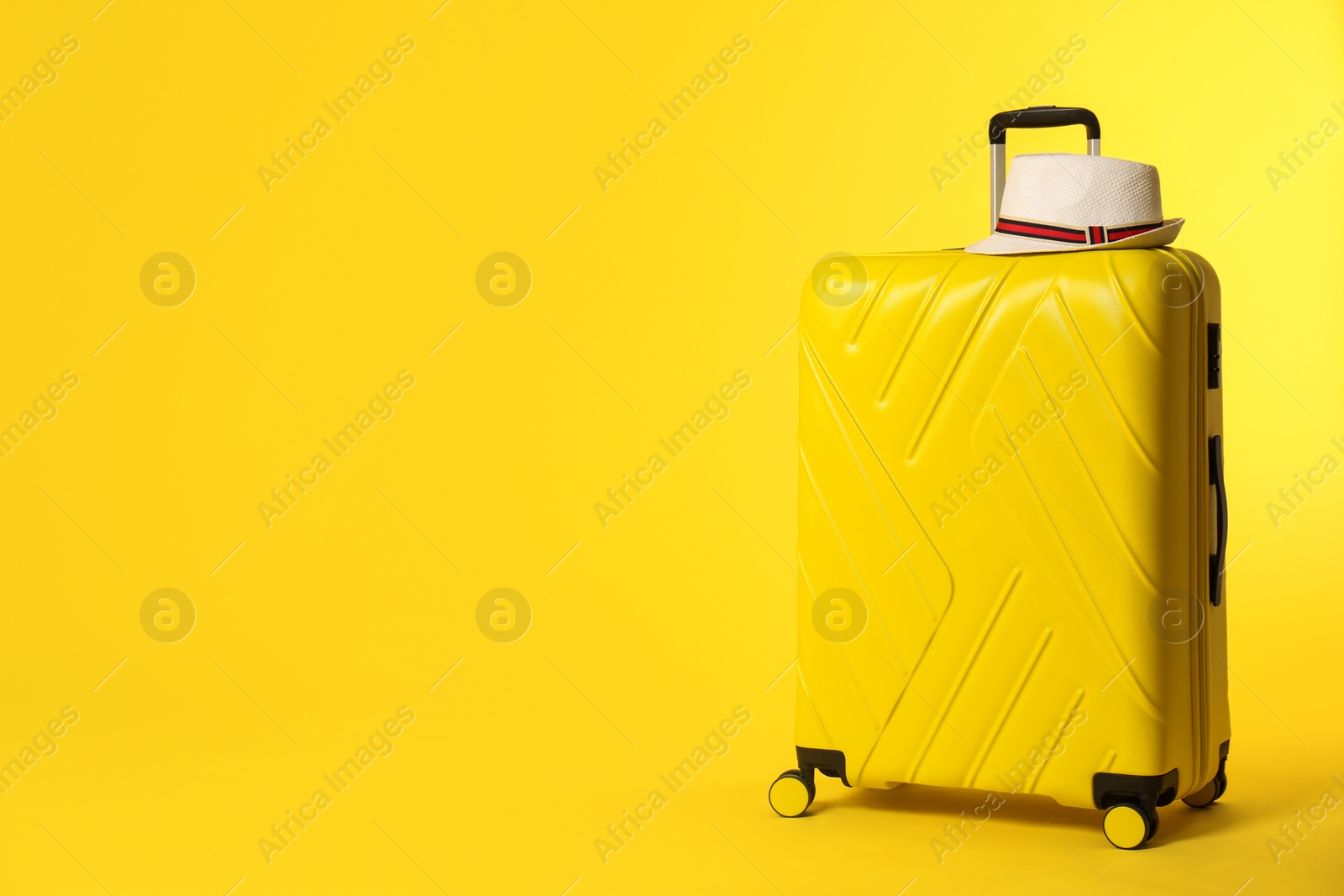 Photo of Bright suitcase with hat on color background. Space for text