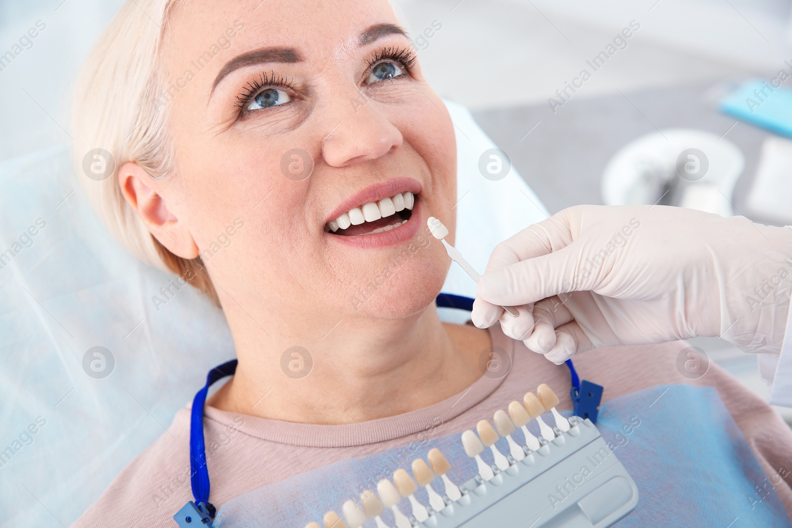 Photo of Dentist selecting patient's teeth color with palette in clinic