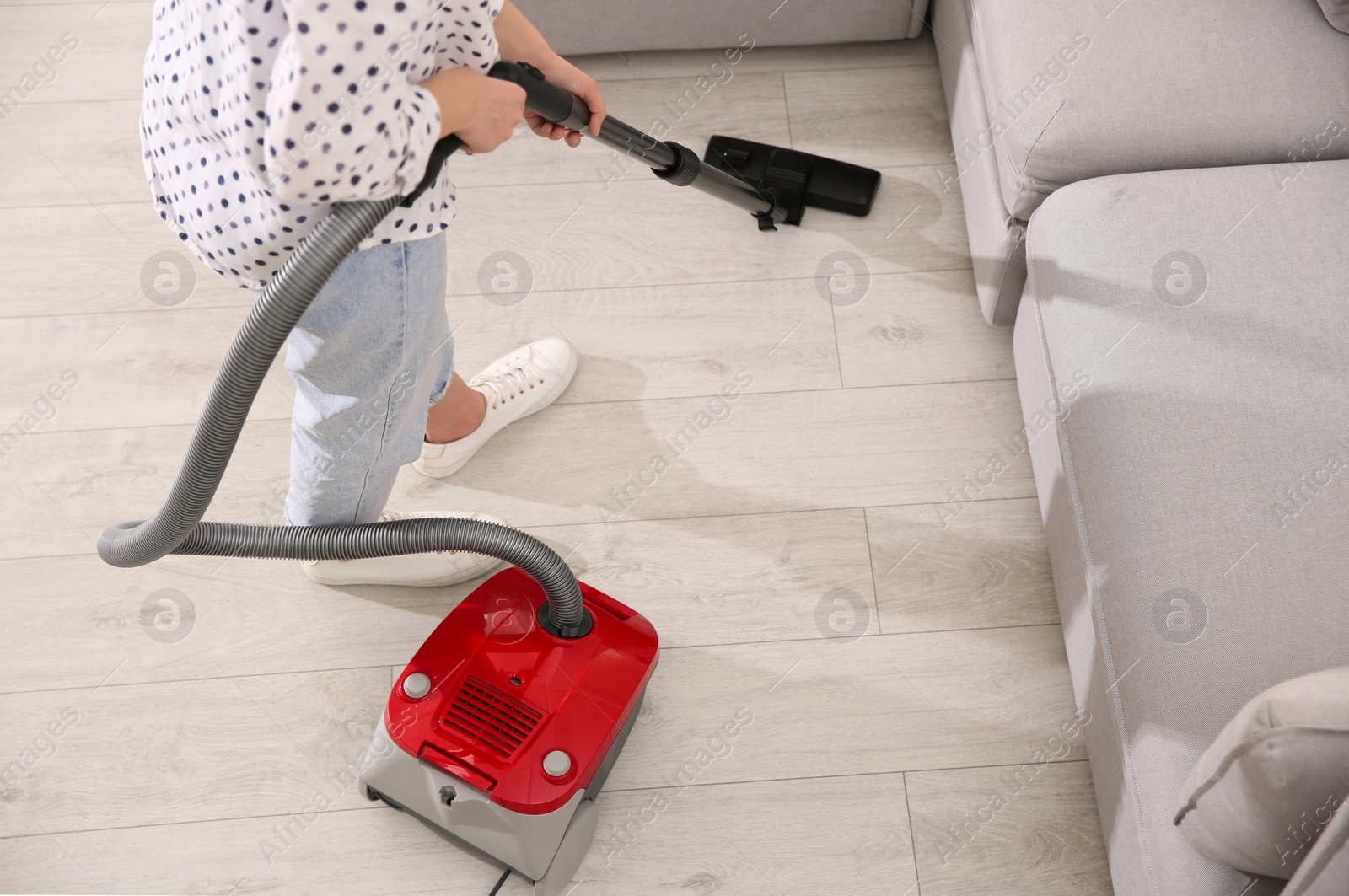 Photo of Young woman using vacuum cleaner at home, closeup