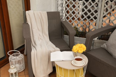 Blanket, pillow, cup of tea and beautiful chrysanthemum flowers on garden furniture outdoors