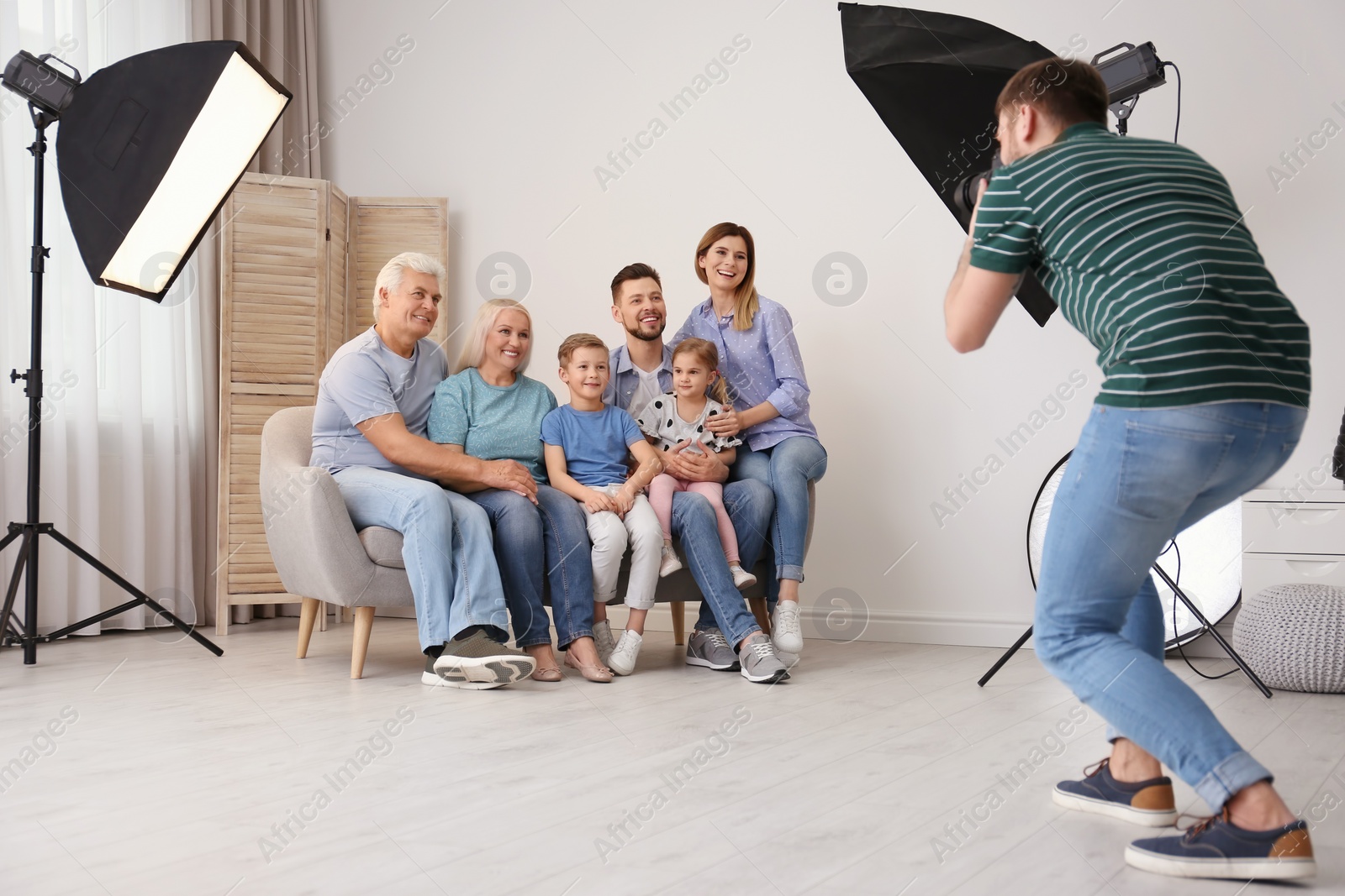 Photo of Professional photographer taking photo of family on sofa in studio