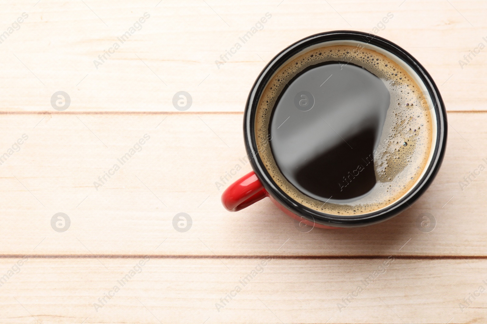 Photo of Cup of aromatic coffee on light wooden table, top view. Space for text