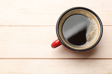 Cup of aromatic coffee on light wooden table, top view. Space for text