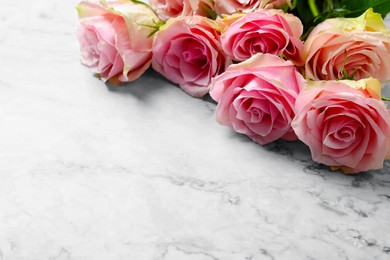 Beautiful bouquet of roses on white marble table, space for text. Happy birthday greetings