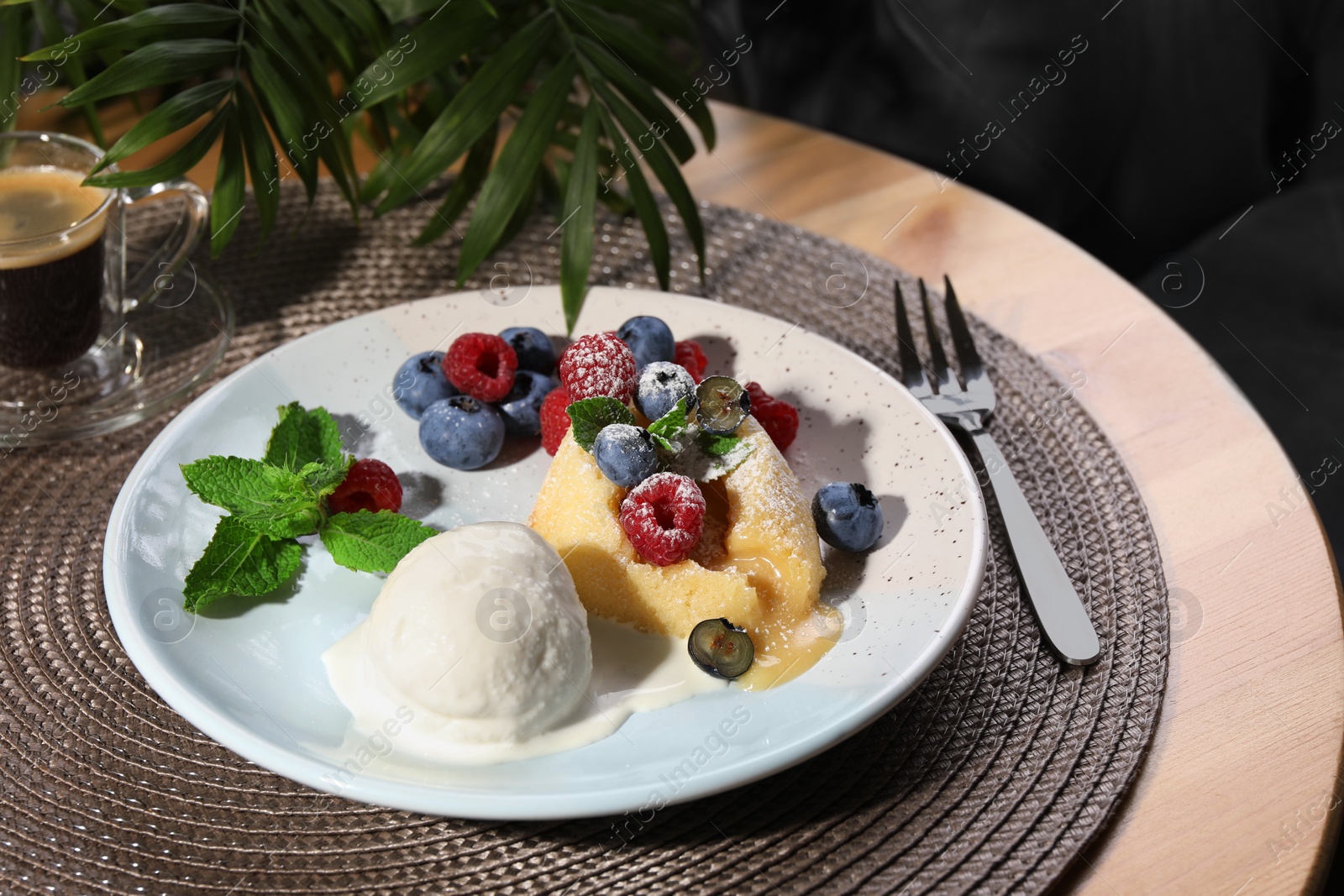 Photo of Delicious vanilla fondant served with ice cream and berries on table