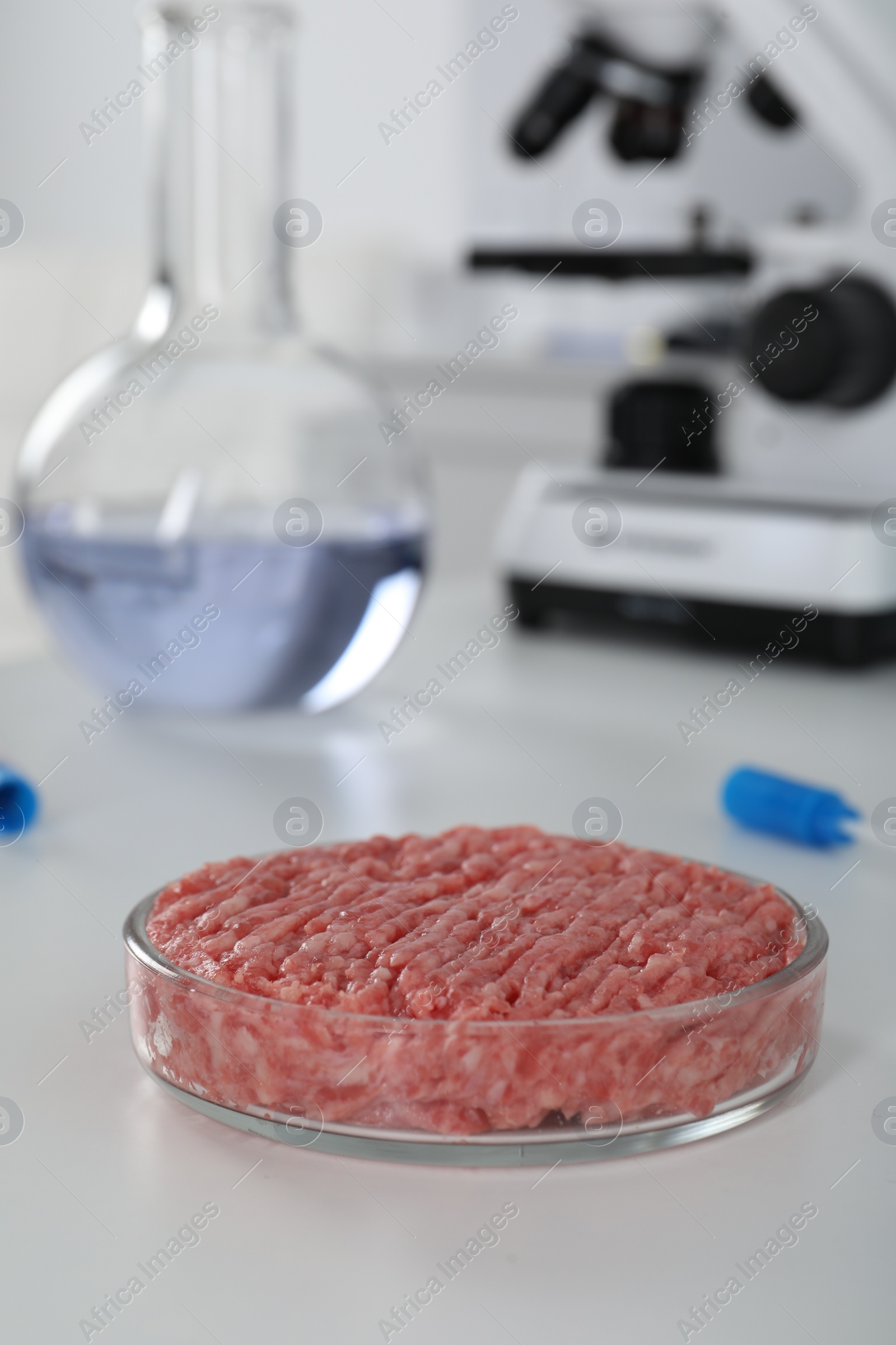 Photo of Petri dish with raw minced cultured meat on white table in laboratory, space for text