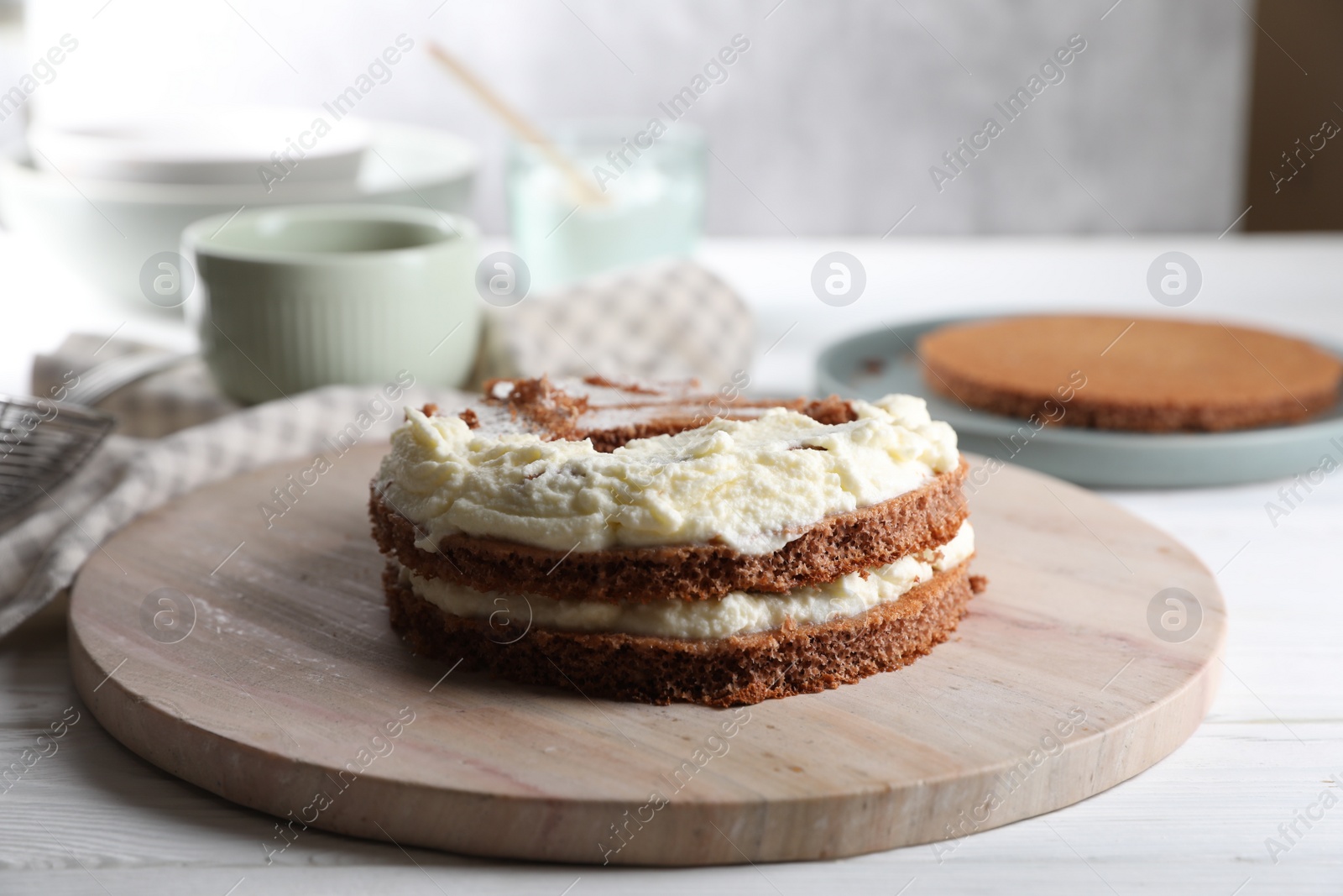 Photo of Delicious homemade layer cake with cream on white wooden table