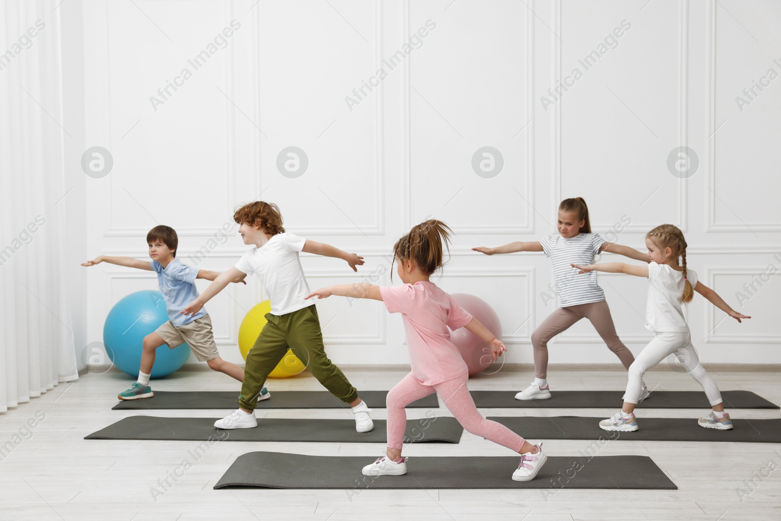 Photo of Group of children doing gymnastic exercises on mats indoors