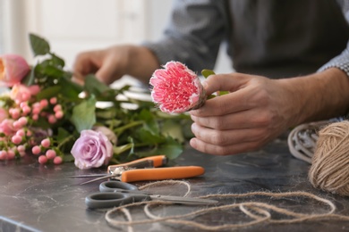 Male florist creating beautiful bouquet at table, closeup