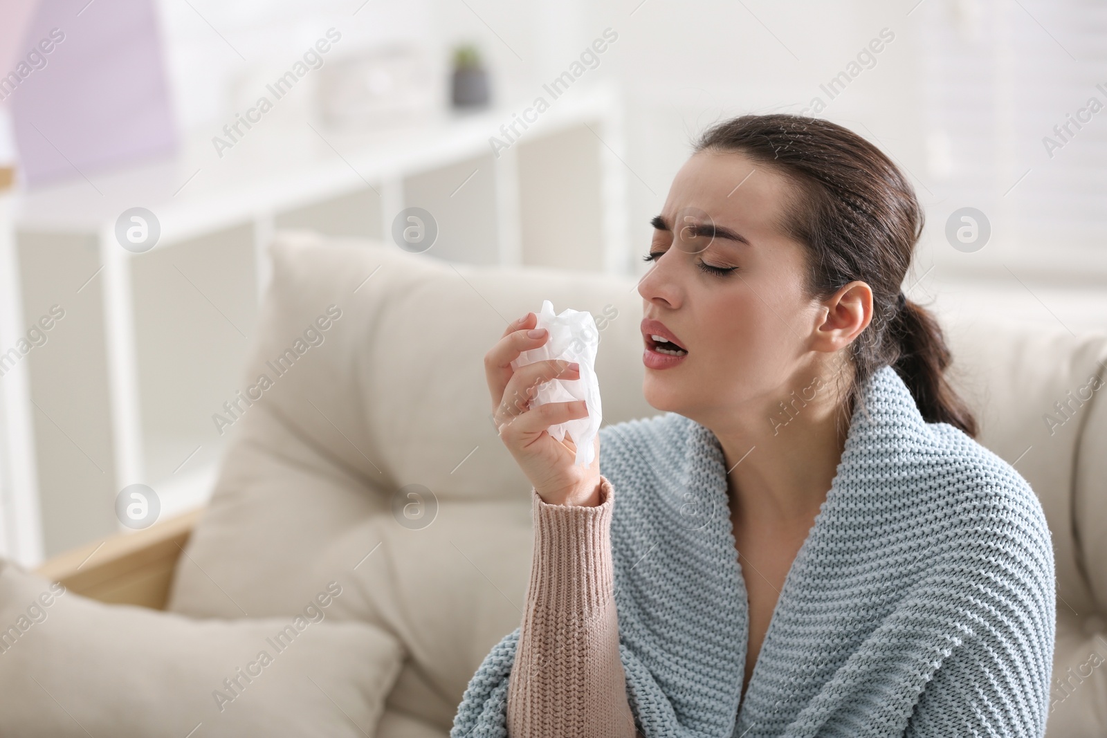 Photo of Young woman suffering from runny nose in living room