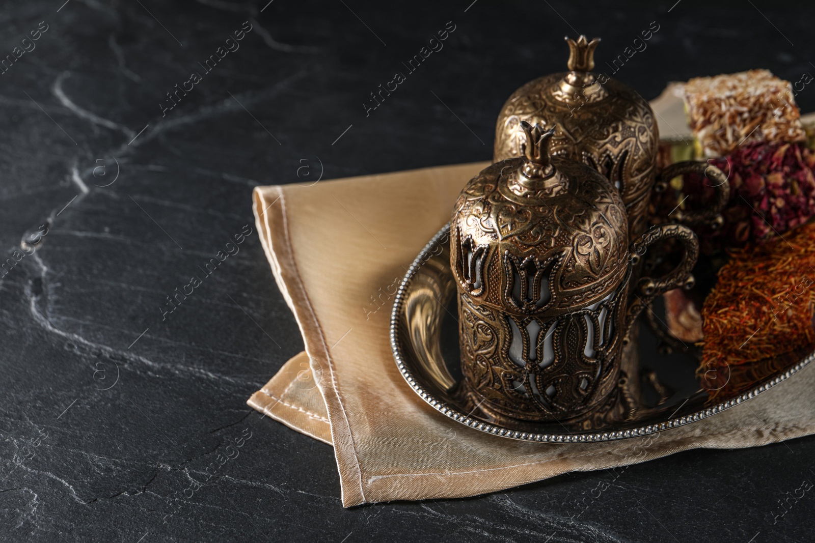 Photo of Tea and Turkish delight served in vintage tea set on dark grey textured table, space for text