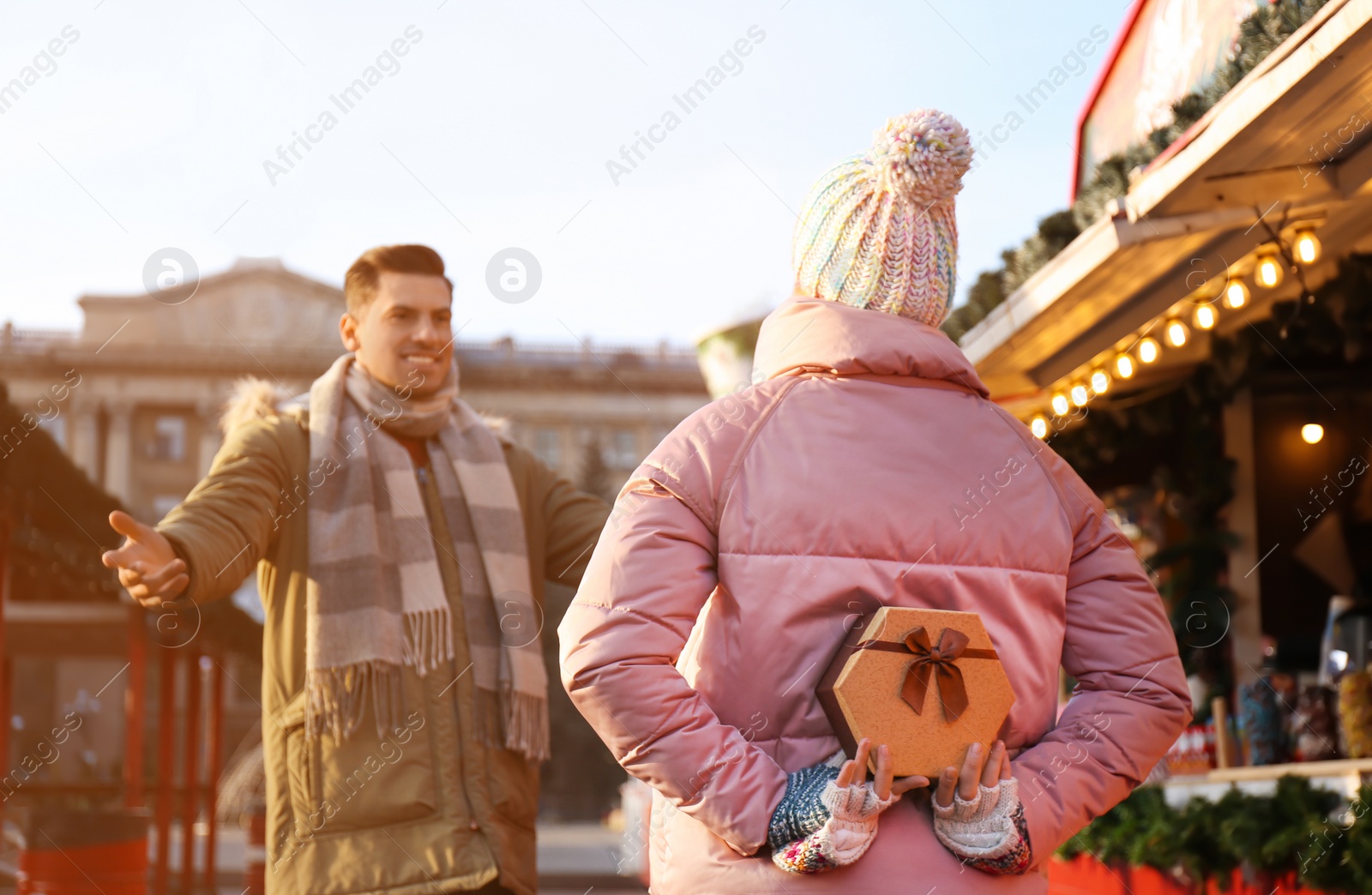 Photo of Young woman presenting Christmas gift to her boyfriend at winter fair