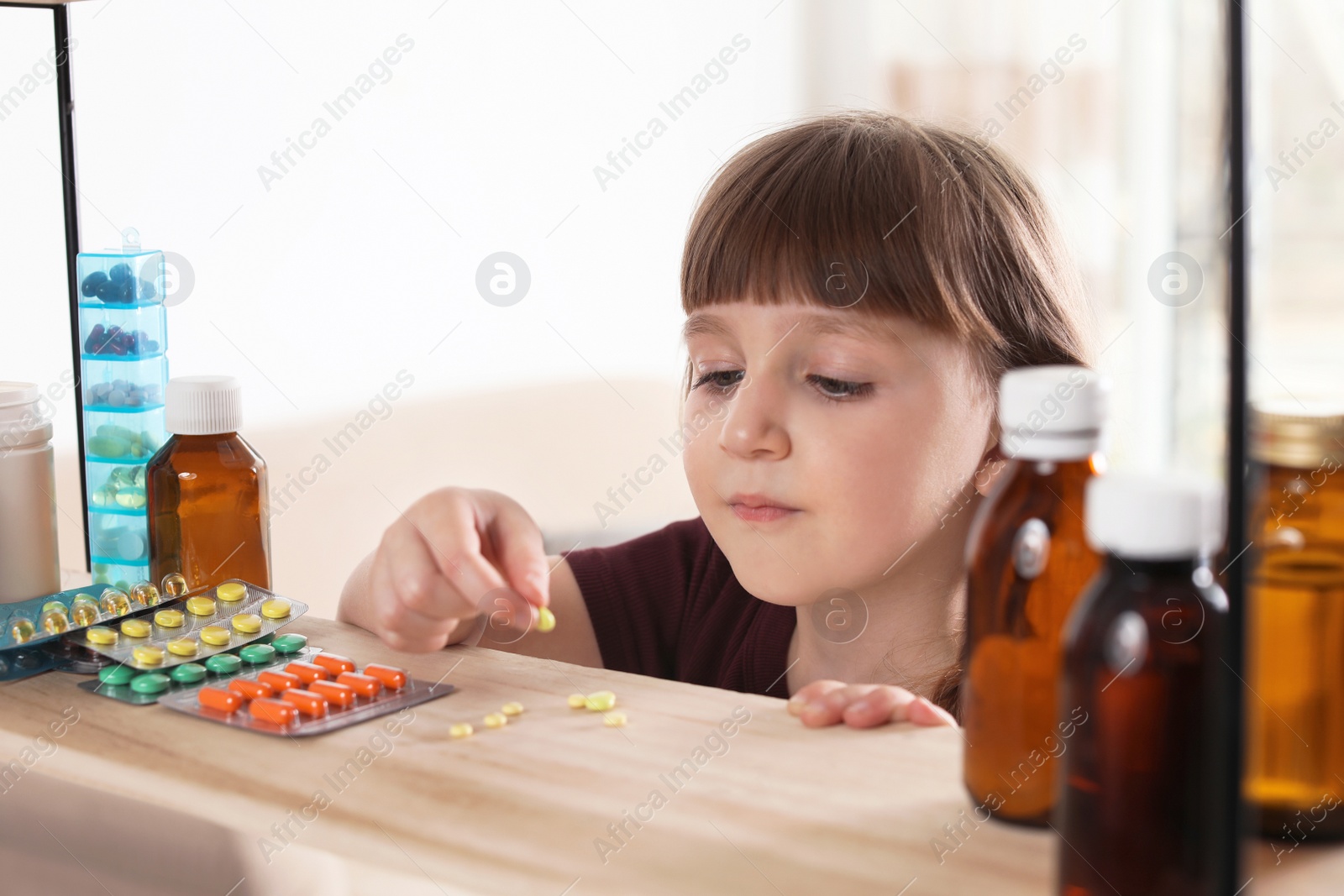 Photo of Little child taking pills from shelf at home. Danger of medicament intoxication