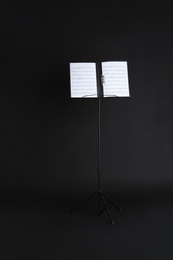 Photo of Note stand with music sheets on black background