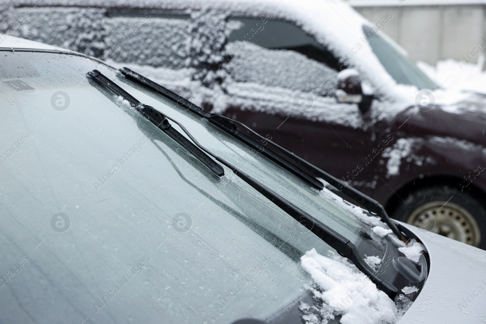 Photo of Car windshield with wiper blades cleaned from snow outdoors on winter day