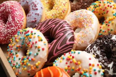 Photo of Yummy glazed donuts with sprinkles, closeup view