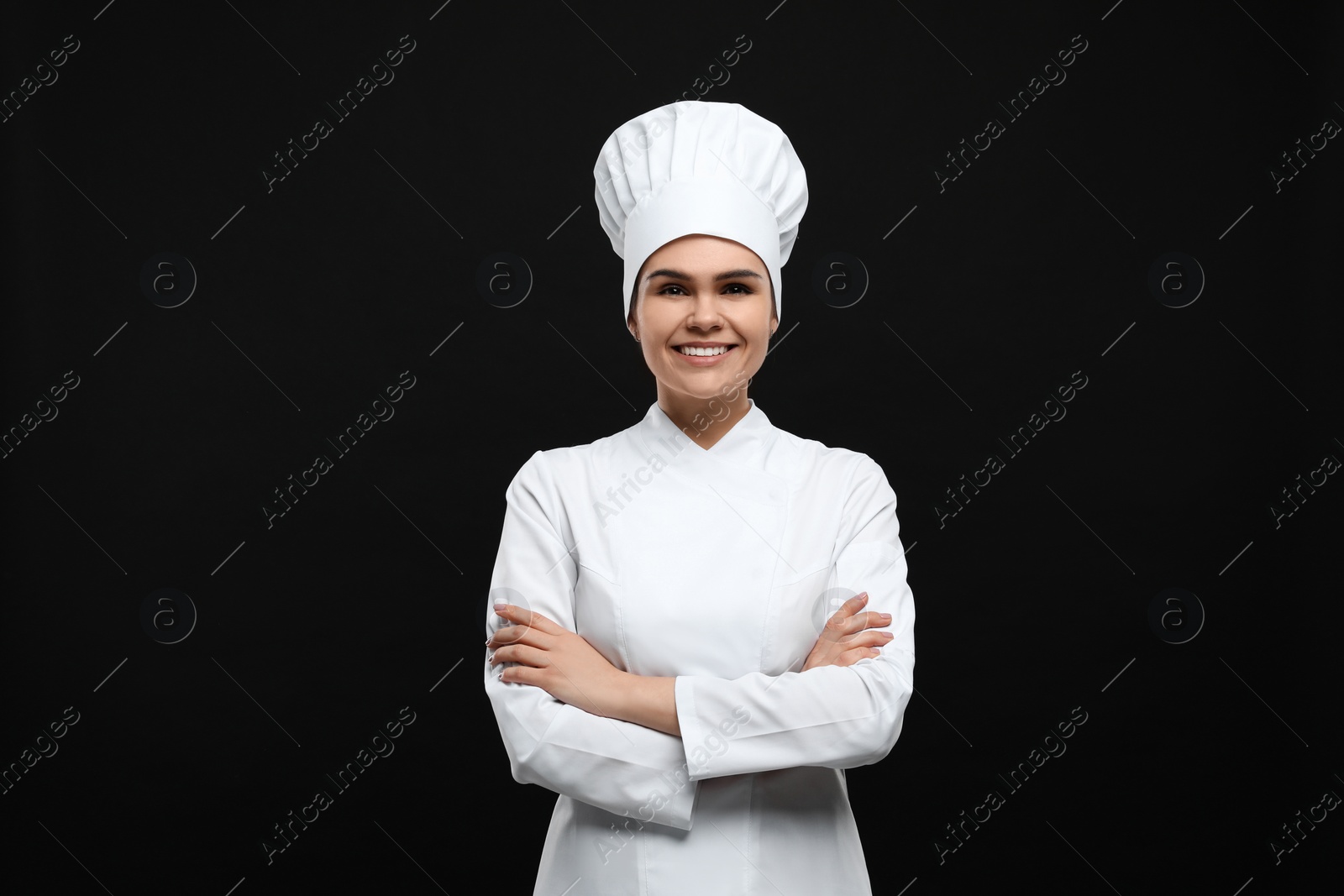 Photo of Happy female chef wearing uniform and cap on black background