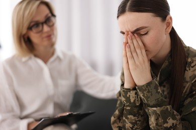 Photo of Psychotherapist working with military woman on sofa in office