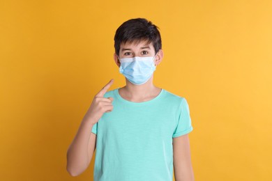 Photo of Boy wearing protective mask on yellow background. Child safety