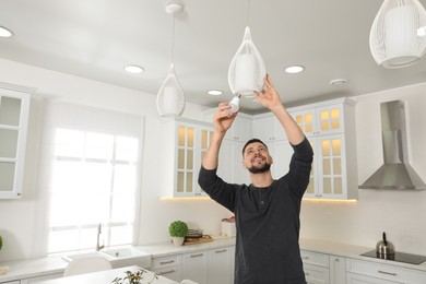 Photo of Man changing light bulb in lamp at home. Space for text