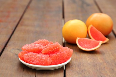 Cut and whole fresh ripe grapefruits on wooden table, space for text