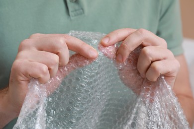 Photo of Man popping bubble wrap, closeup view. Stress relief